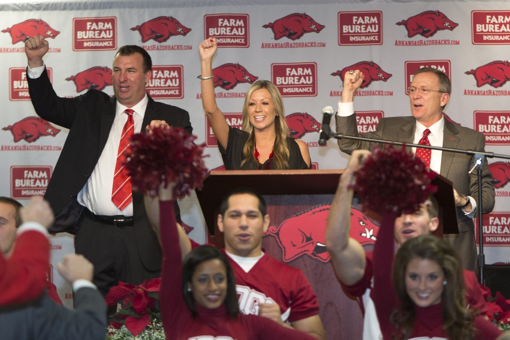 FAYETTEVILLE, AR - DECEMBER 5:  (L - R) Former Wisconsin Badger Head Coach Bret Bielema, his wife Jen and Athletic Director Jeff Long call the Hogs at the press conference to introduce Bret as the new Head Coach of the Arkansas Razorbacks on December 5, 2012 in Fayetteville, Arkansas.  (Photo by Wesley Hitt/Getty Images)
