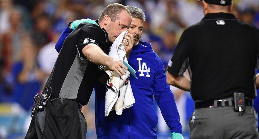 Umpire Nate Tomlinson is helped by Dodgers' trainer Nate Lucero after being hit by a broken bat.