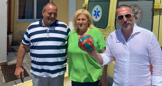 Ivan, right, with his father (left), Kassandra mayor Anastasia Chalkia (center), and the soccer ball that helped him survive a sea ordeal.