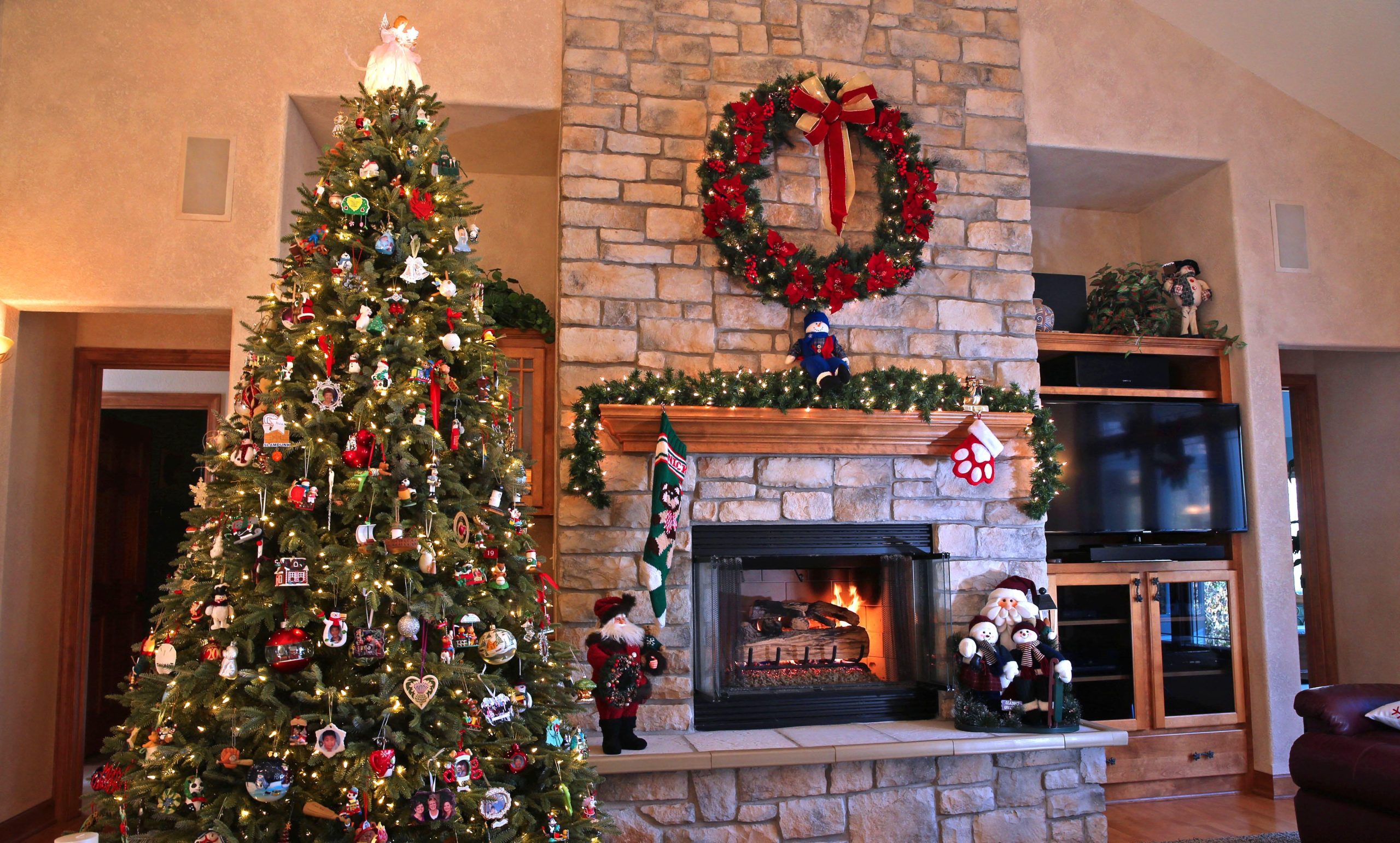 A Christmas tree next to a fireplace.