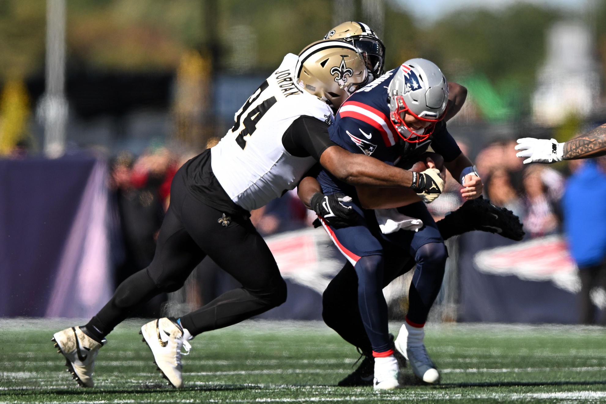 Oct 8, 2023; Foxborough, Massachusetts, USA; New England Patriots quarterback Mac Jones (10) is sacked by New Orleans Saints defensive end Tanoh Kpassagnon (92) and defensive end Cameron Jordan (94) during the first half at Gillette Stadium. Mandatory Credit: Brian Fluharty-USA TODAY Sports