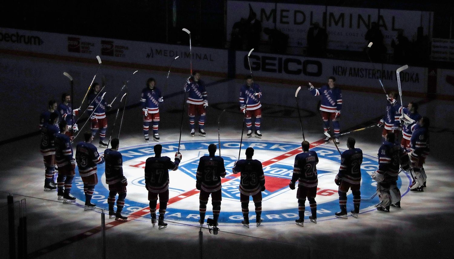 New York Rangers players huddle around the center ice logo as they prepare for the home opener against the New York Islanders at Madison Square Garden.
