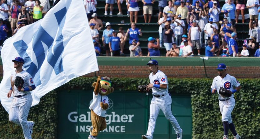 Chicago Cubs mascot Clark runs with the W flag as Chicago Cubs left fielder Ian Happ (left) right fielder Seiya Suzuki (center) and center fielder Rafael Ortega (right) celebrate their win against the Miami Marlins at Wrigley Field.