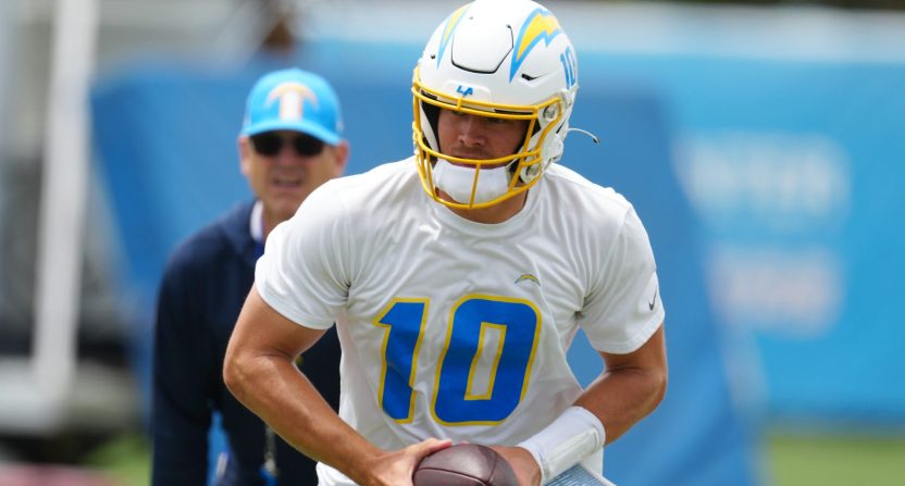 Los Angeles Chargers quarterback Justin Herbert (10) hands the ball off as coach Jim Harbaugh watches during organized team activities at the Hoag Performance Center. Mandatory Credit: Kirby Lee-USA TODAY Sports