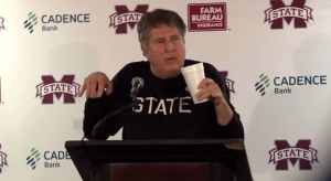 Mike Leach giving a press conference on dinosaur hands.