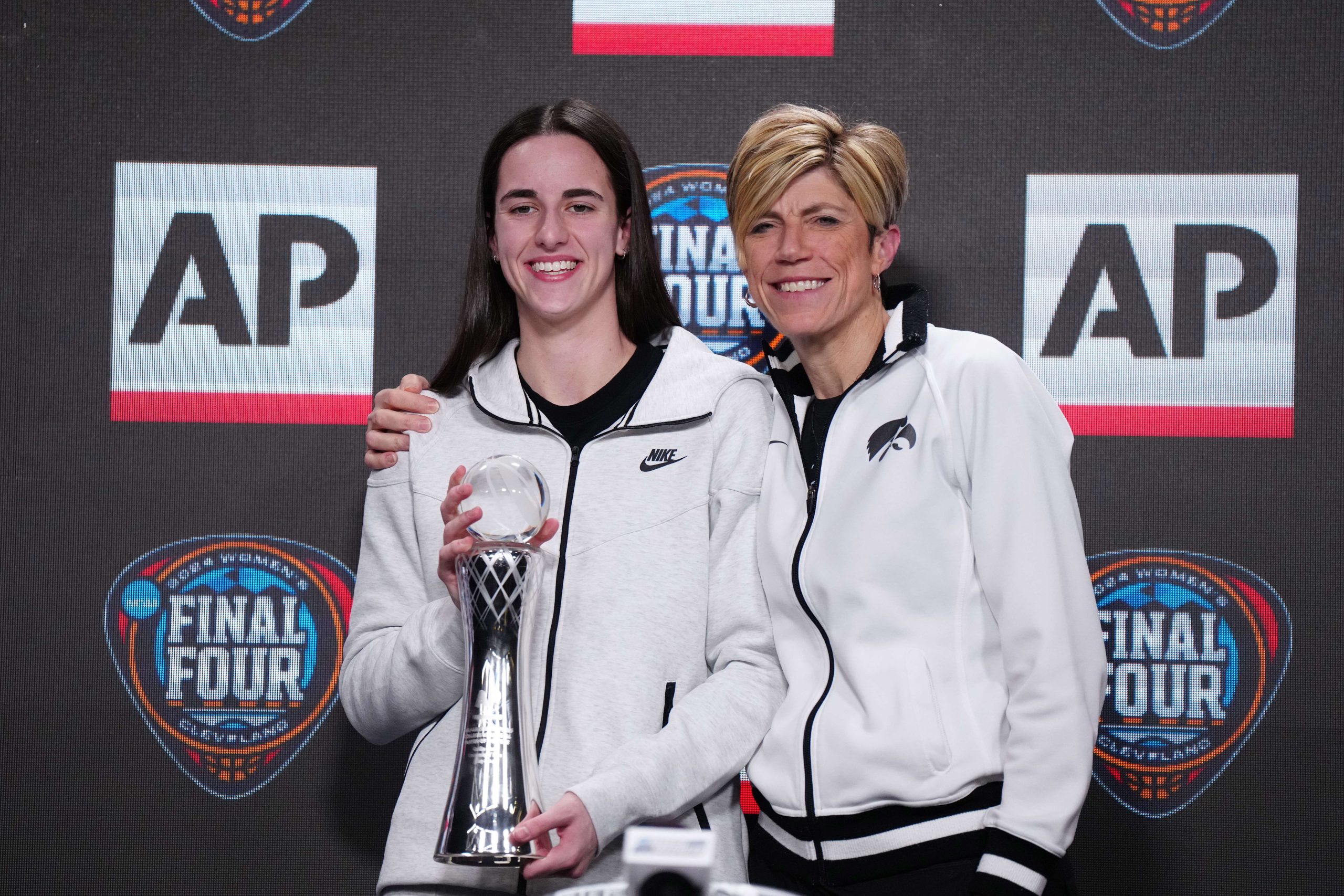 Apr 4, 2024; Cleveland, OH, USA; Iowa Hawkeyes guard Caitlin Clark (left) poses with associate head coach Jan Jensen after being selected as the AP Player of the Year at a press conference at Rocket Mortgage FieldHouse.