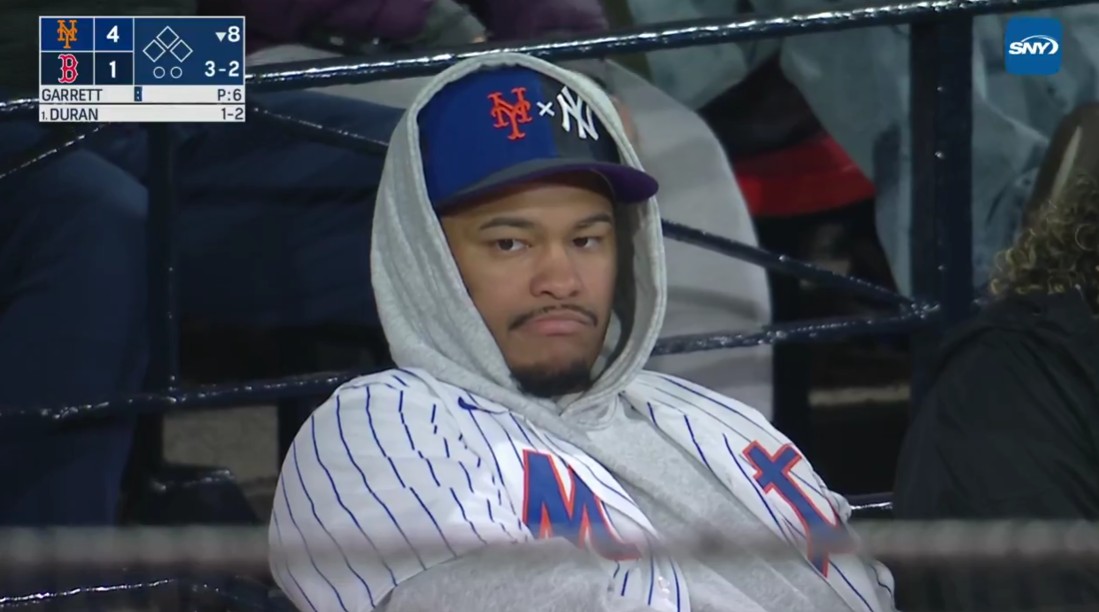 A fan watches a Mets-Red Sox game as SNY's Gary Cohen criticizes hit Yankees-Mets split hat. Photo Credit: SNY