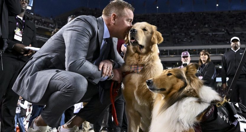 Nov 30, 2024; College Station, Texas, USA; ESPN's Kirk Herbstreit, left, speaks to his dog Peter while meeting the Texas A&M mascot Reveille X prior to the game against the Texas Longhorns. The Longhorns defeated the Aggies 17-7 at Kyle Field. Mandatory Credit: Maria Lysaker-Imagn Images