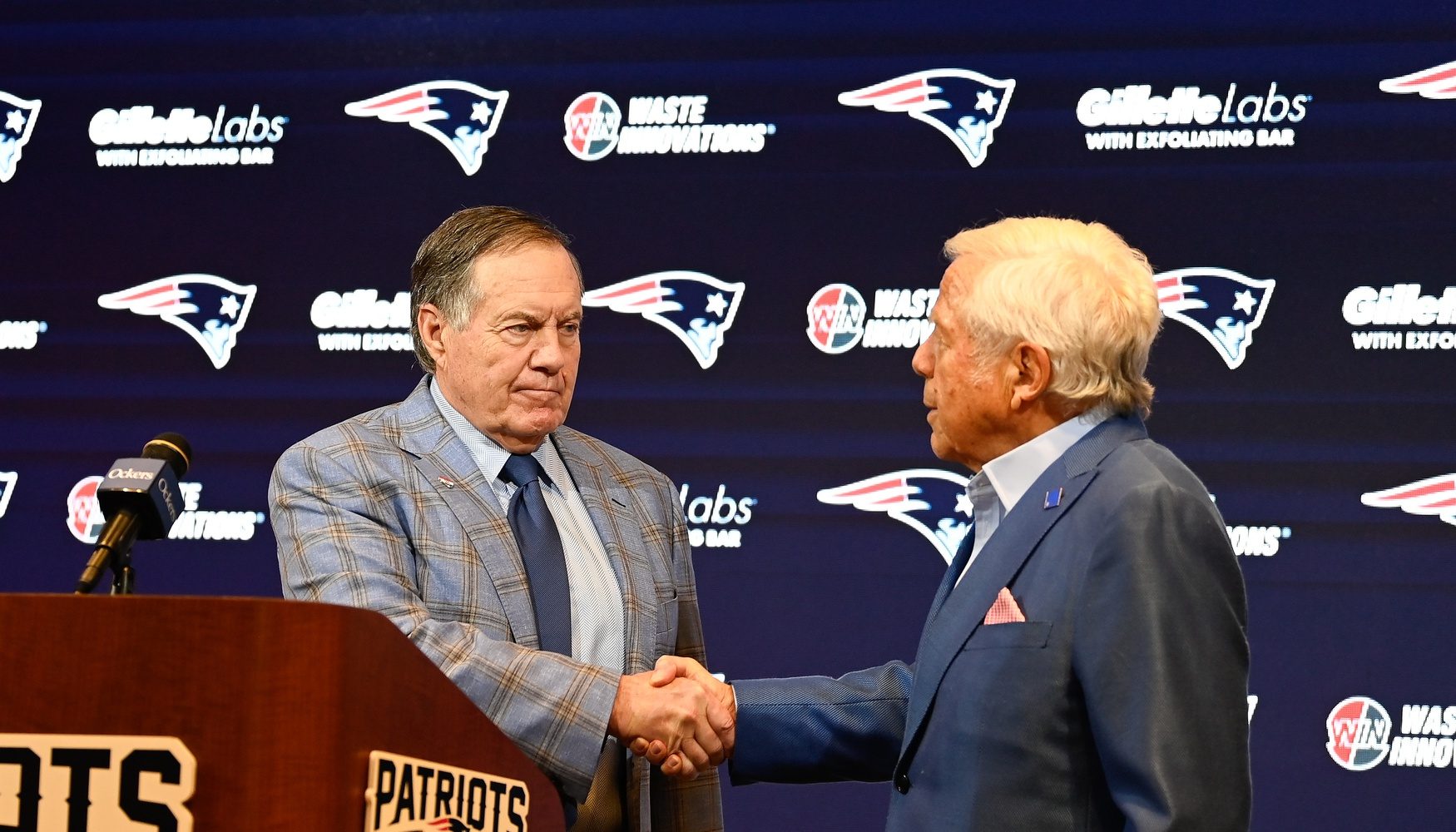 New England Patriots former head coach Bill Belichick (left) shakes hands with Patriots owner Robert Kraft (right) during a press conference at Gillette Stadium to announce Belichick's exit from the team.