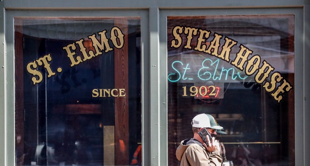Fans walk past St. Elmo Steak House during the 2021 NCAA Final Four tournament on Monday, April 5, 2021, in downtown Indianapolis.