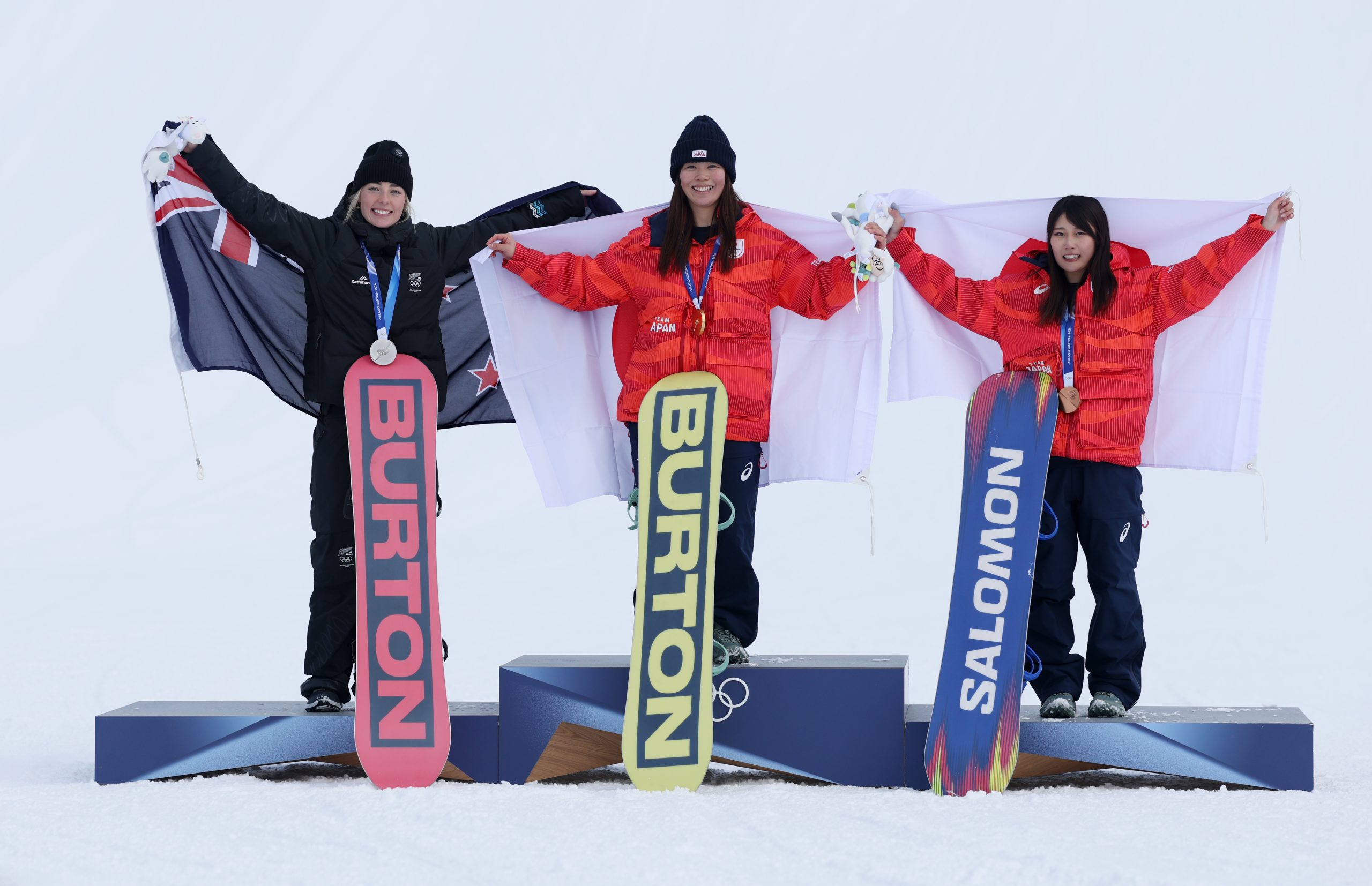 Feb 18, 2026; Livigno, Italy; From left Zoi Sadowski Synnott of New Zealand, Mari Fukada of Japan and Kokomo Murase of Japan celebrate on the podium with their medals in the women's snowboarding slopestyle final during the Milano Cortina 2026 Olympic Winter Games at Livigno Snow Park. Mandatory Credit: Nathan Ray Seebeck-Imagn Images