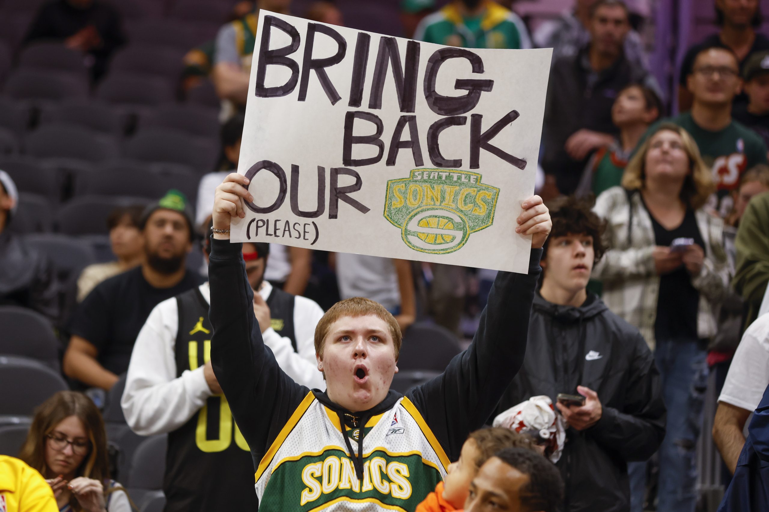 Oct 10, 2023; Seattle, Washington, USA; A Seattle Supersonics fan holds a sign advocating for their return during pregame warmups between the LA Clippers and Utah Jazz at Climate Pledge Arena. Mandatory Credit: Joe Nicholson-USA TODAY Sports