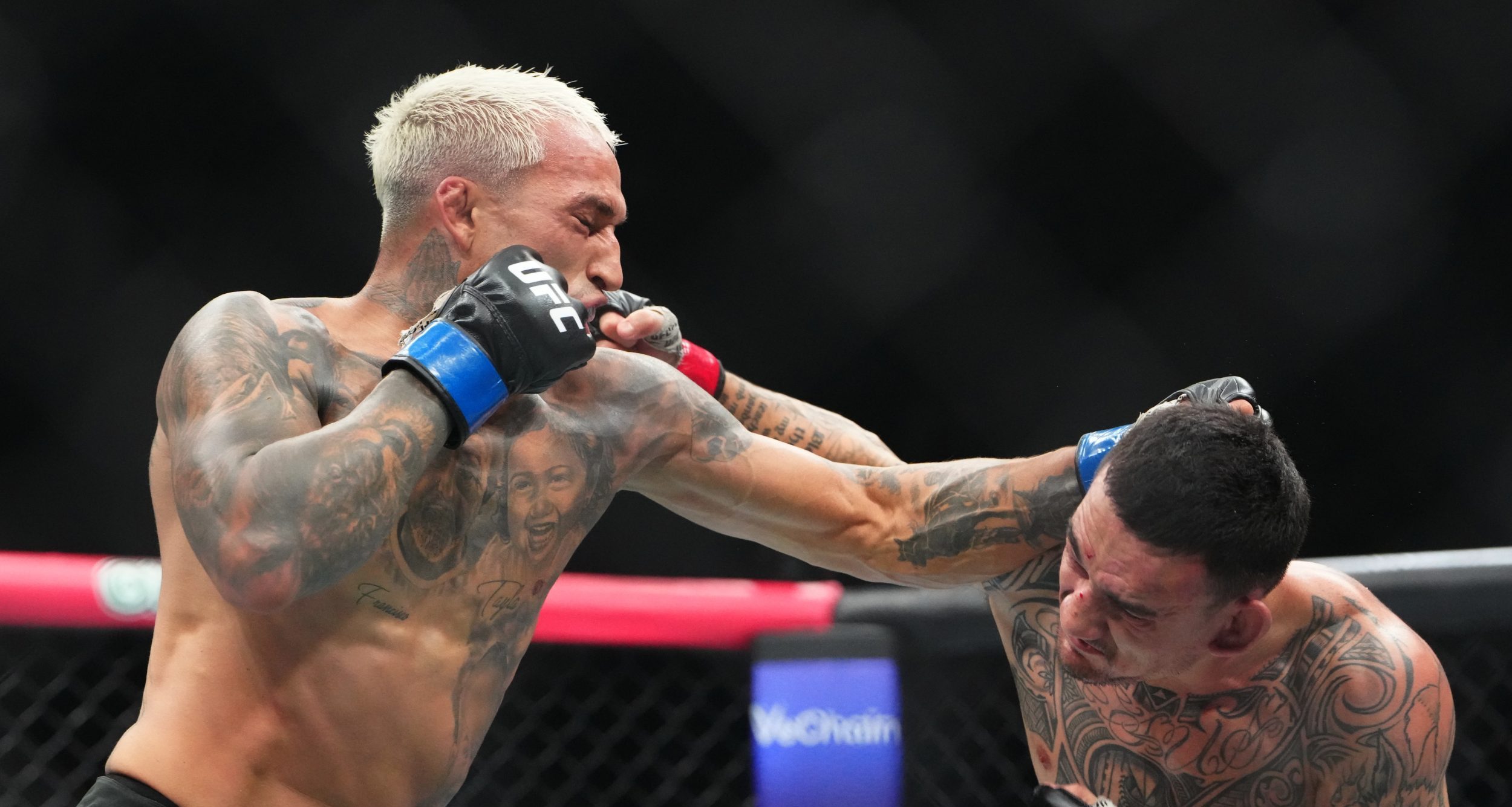 Max Holloway (red gloves) fights Charles Oliveira (blue gloves) during UFC 326