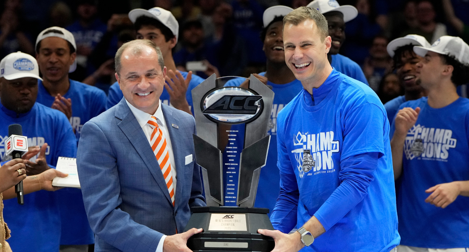 Mar 15, 2025; Charlotte, NC, USA; ACC Commissioner Jim Phillips hands the championship trophy to Duke Blue Devils head coach Jon Scheyer after the 2025 ACC Conference Championship game against the Louisville Cardinals at Spectrum Center. Mandatory Credit: Jim Dedmon-Imagn Images