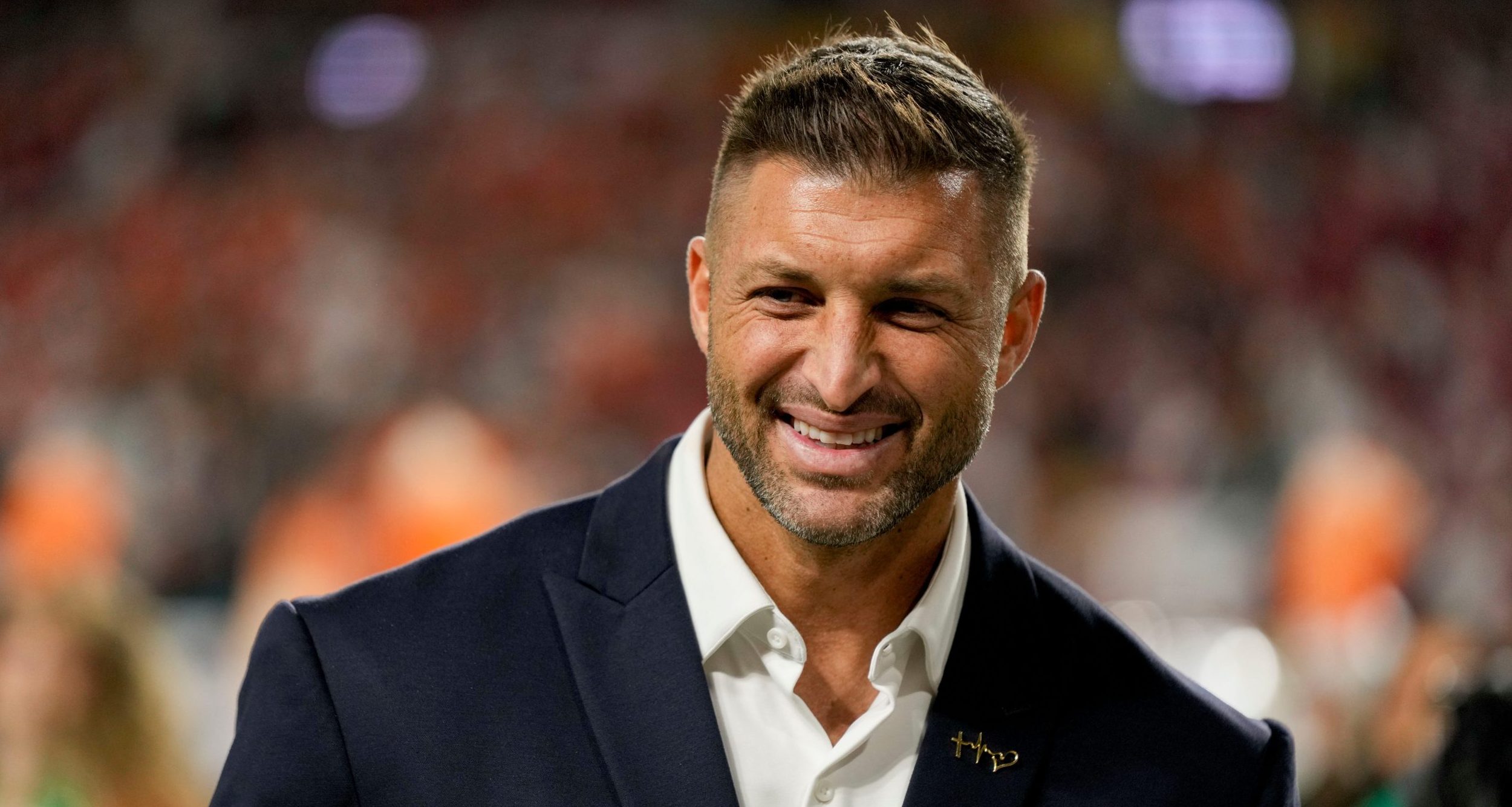 Tim Tebow stands on the sidelines